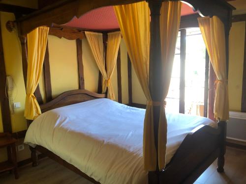 a bedroom with a canopy bed with yellow curtains at Auberge du Renard'eau in Bèze