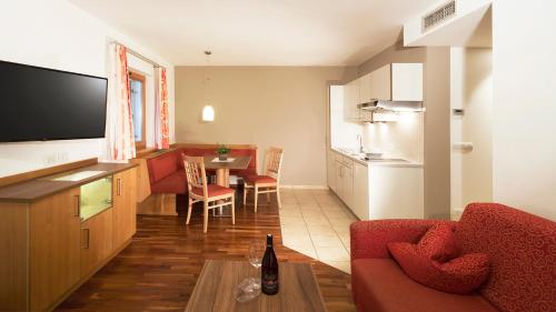 a living room with a red couch and a kitchen at Hotel Sonnenhof in Marlengo
