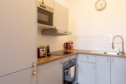 une cuisine avec des placards blancs et une horloge murale dans l'établissement DIFY Magique - Part Dieu, à Villeurbanne