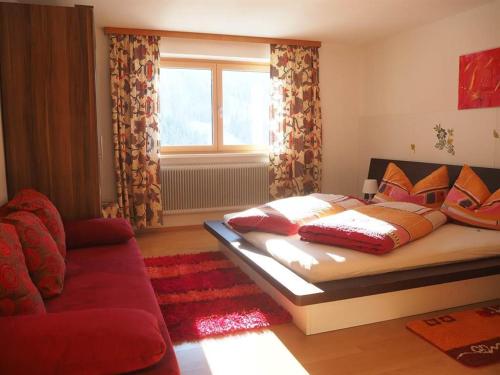 sypialnia z łóżkiem, kanapą i oknem w obiekcie Ferienwohnung Hildegard w mieście Silbertal