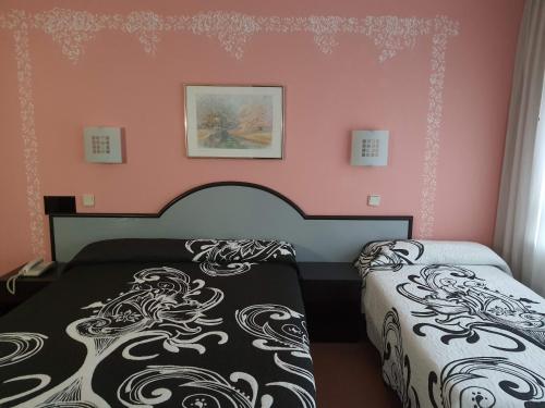 a bedroom with two beds and pink walls at Hotel Arha Santander in Santander