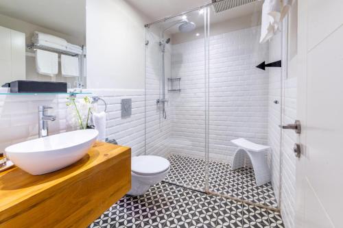 a bathroom with a sink and a toilet and a shower at Jacob Shenkin Hotel in Tel Aviv