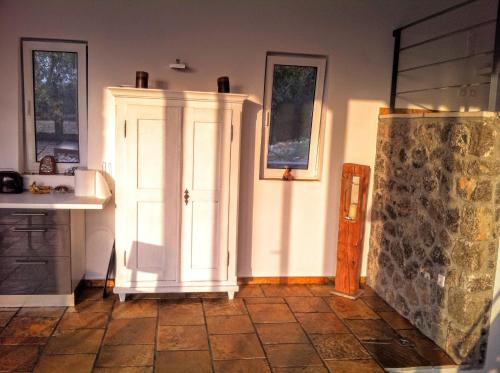 a kitchen with a white cabinet and a tile floor at Natur-Steinhaus mit Meerblick: hell, ruhig, exklusiv, strandnah in Liapades