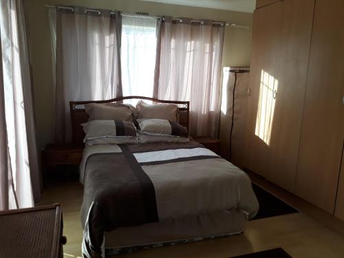1 dormitorio con cama con almohadas y ventana en Robertsham (Halaal) Self Catering Cottages, en Johannesburgo