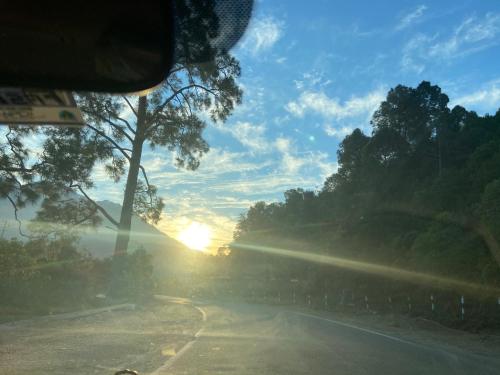 a view from a car windshield of a road with the sunset at HOTEL THE TARANANT in Katra