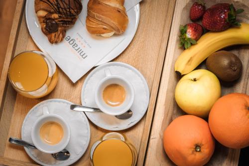 a wooden table with two cups of coffee and fruit at Lake Front Hotel Mirage in Riva del Garda