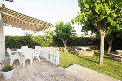 a patio with a white table and chairs in a yard at Nuvolet Apartaments in Cala en Blanes