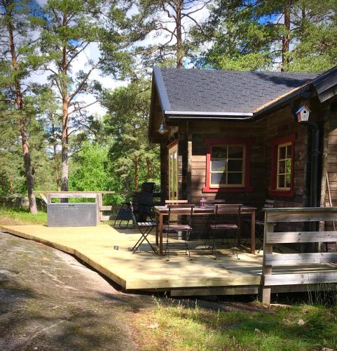 a log cabin with a table and chairs on a deck at Tofvehults Boende in Skaftet
