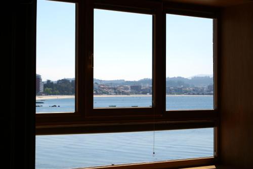 a window with three views of a body of water at A Esmorga-Posada del Mar in Vilagarcia de Arousa