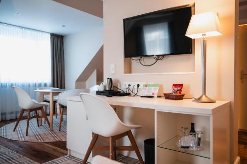 a hotel room with a bar with chairs and a flat screen tv at Hotel Birke, Ringhotel Kiel in Kiel