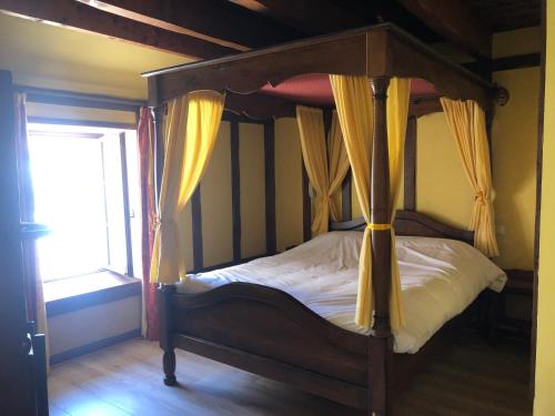 a bedroom with a canopy bed with yellow curtains at Auberge du Renard'eau in Bèze