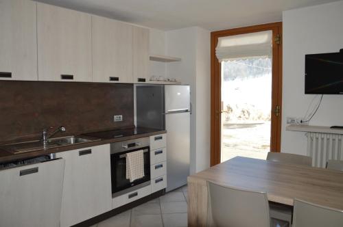 a kitchen with white cabinets and a table and a sink at Chalet Aura in Livigno