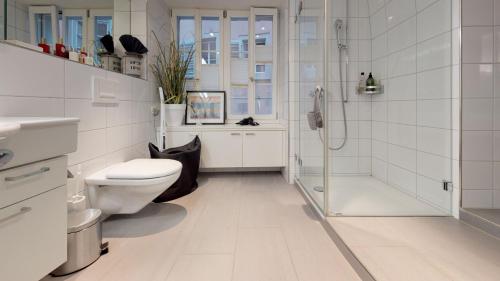 a white bathroom with a shower and a toilet at Signature Bijou in Zurich