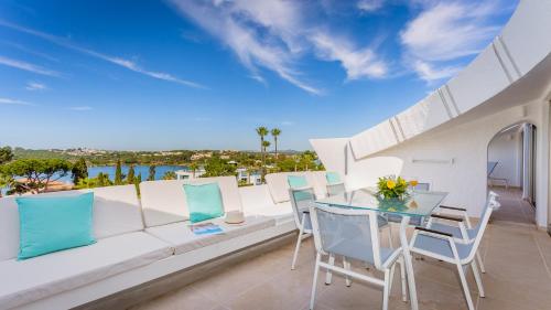 a balcony with a white couch and a table and chairs at Quinta do Lago Country Club in Quinta do Lago