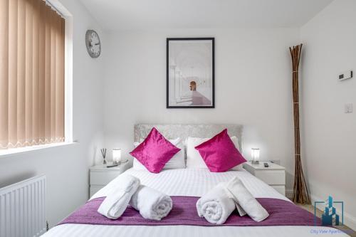 biała sypialnia z różowymi poduszkami i łóżkiem w obiekcie City View Apartments B5 Central City Centre w Birmingham