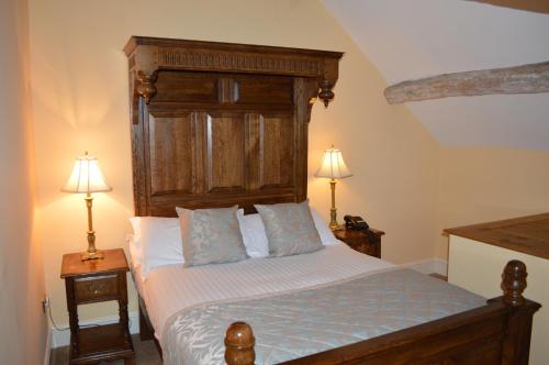 a bedroom with a bed with a wooden headboard and two lamps at Brigands Inn in Mallwyd