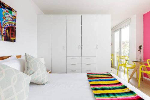 a bedroom with a white bed with a colorful rug on the floor at MyPlace at Santo Domingo in Mexico City
