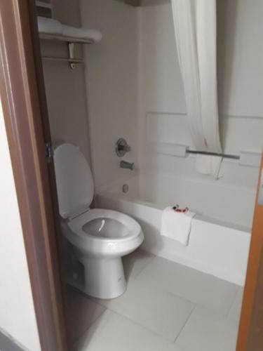 a white bathroom with a toilet and a tub at Baymont Inn & Suites Richmond in Richmond