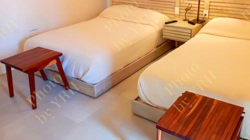 two beds in a small room with a table and a stool at Esciros in Chicxulub