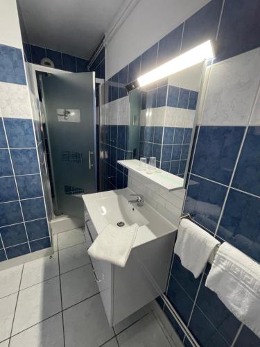a blue tiled bathroom with a sink and a shower at Sarl Macarena in Pouillenay