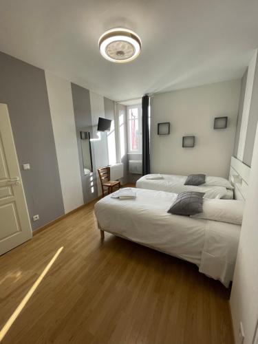 a bedroom with a large white bed and a wooden floor at Sarl Macarena in Pouillenay