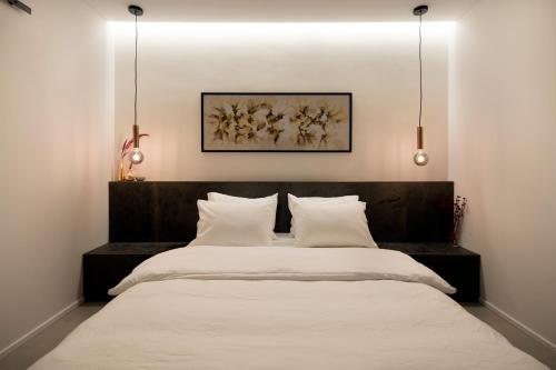 a bedroom with a large bed with white sheets at Urbanica Carmel- Apartments in Haifa