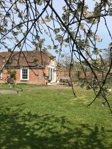 a house in a field with a yard with a tree at The Workshop @ The Grange in Lydd