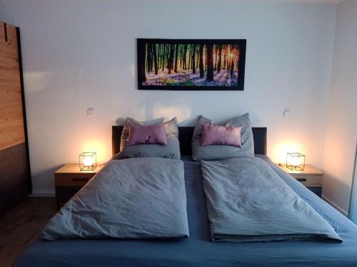 a bedroom with a bed with two pillows and a painting on the wall at Ferienwohnung Hegaublüte in Engen