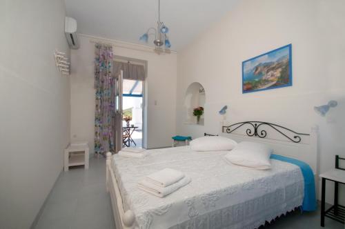 ein weißes Schlafzimmer mit einem Bett mit Handtüchern darauf in der Unterkunft Filio rooms in Kýthira