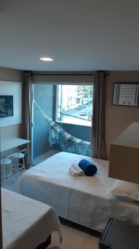 a hotel room with two beds and a window at Pousada São Pedro in São Pedro da Aldeia