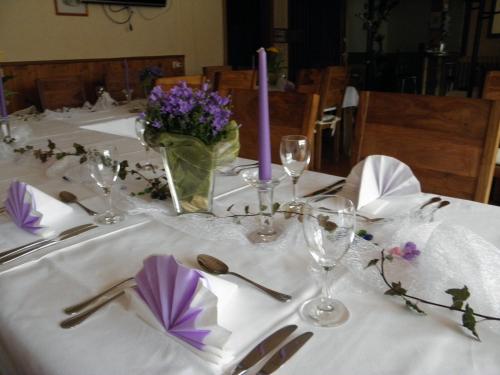 a table with a white table cloth and purple flowers at Alb Hotel Schalksburg in Albstadt