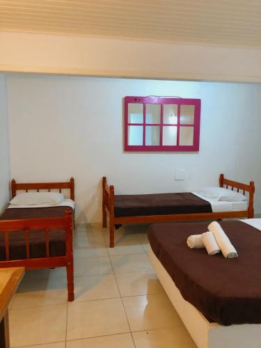 a room with three beds and a window at Anexo Aldeia Búzios in Búzios