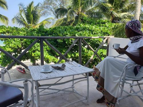 a woman sitting on a chair on a patio with a table at Ayla Beach House in Kiwengwa