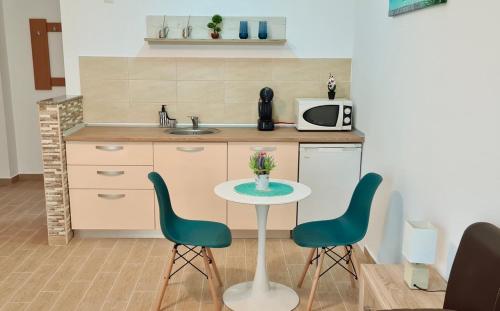 kuchnia ze stołem, 2 krzesłami i kuchenką mikrofalową w obiekcie Studio Escape Mamaia next by LOFT w Mamai