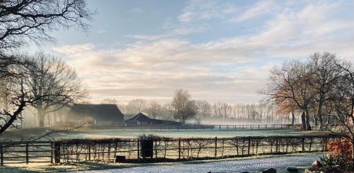 a farm with a fence and a barn in a field at De Vijf Suites in Elp