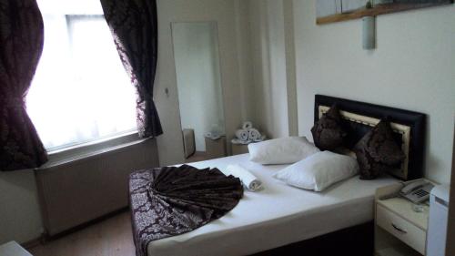 a bedroom with a bed with white sheets and a window at Bade Otel in Istanbul