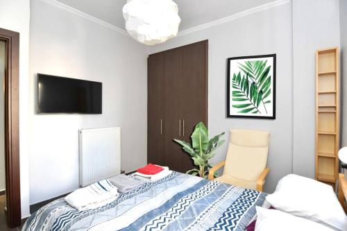 a bedroom with a bed and a tv and a chair at Modern apartment in the heart of the city in Larisa