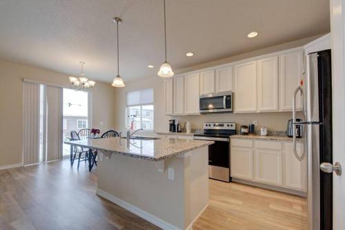 a kitchen with white cabinets and a table with chairs at Large Brand-New Home Close to Lake & Mountains in Monument