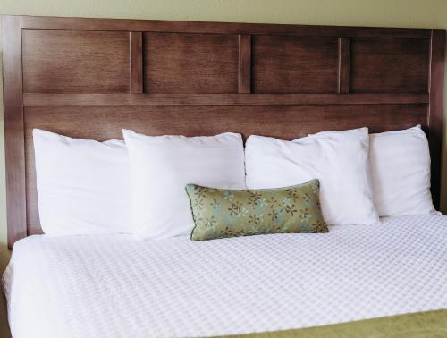 a bed with white pillows and a wooden headboard at Pacific Inn Motel in Forks