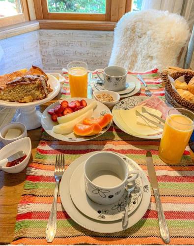 a table topped with plates of food and drinks at Pousada Canto do Sabiá in Monte Verde