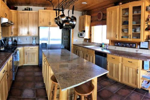 a large kitchen with wooden cabinets and a large island at Red Rock Ranch Log Cabin: Large, Fully Furnished in Escalante