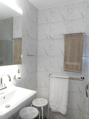 La salle de bains blanche est pourvue d'un lavabo et d'un miroir. dans l'établissement Casa Pignia, à Laax