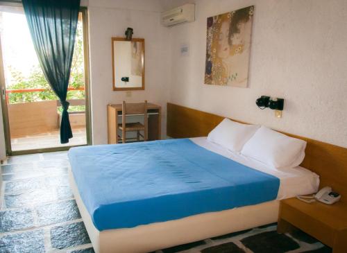 a bedroom with a bed with blue sheets and a window at Apollonia Hotel Apartments in Varkiza
