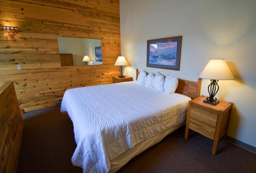 1 dormitorio con 1 cama y pared de madera en The Inn at Silvercreek, en Granby