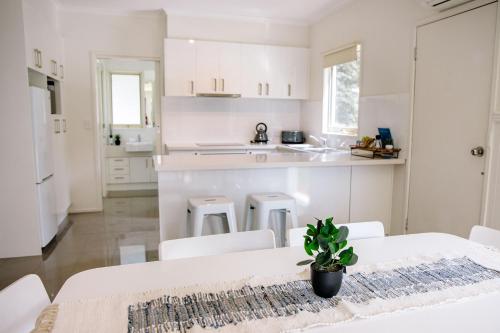 a kitchen with white cabinets and a table with a potted plant at McMillans of Metung Coastal Resort in Metung