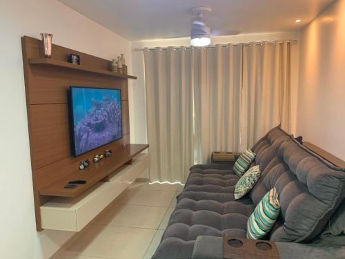 a living room with a couch and a flat screen tv at Apartamento Le Bon Vivant Arraial do Cabo in Arraial do Cabo