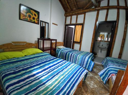 a bedroom with two beds and a bathroom at Hospedaje El Jardín in San Agustín