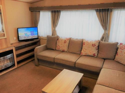 a living room with a couch and a flat screen tv at Laurel Superior Holiday Home in Mablethorpe
