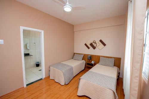a room with two beds and a shower at Imperador Hotel in Poços de Caldas