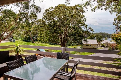 a table and chairs on a balcony with trees at McMillans of Metung Coastal Resort in Metung